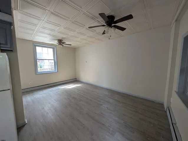 a view of an empty room with wooden floor and window
