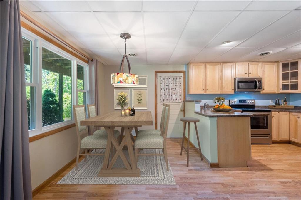234 Sky Top Road Acme, PA 15610 - Photo 3 of 19 a kitchen with stainless steel appliances kitchen island granite countertop a stove a refrigerator a sink a dining table and chairs with wooden floor