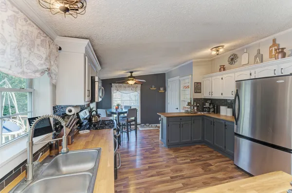 a kitchen with stainless steel appliances granite countertop a refrigerator a stove top oven a dining table and chairs with wooden floor
