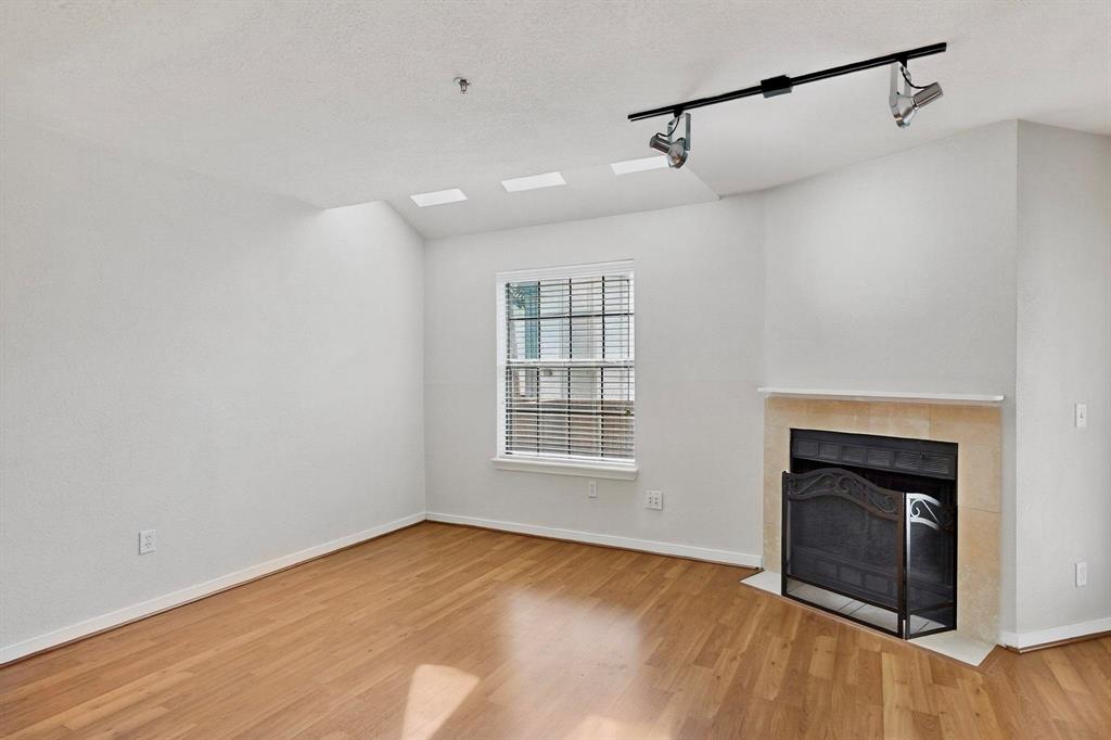 3901 Travis Street, Unit 113 Dallas, TX 75204 - Photo 18 of 40 a view of empty room with wooden floor and fireplace