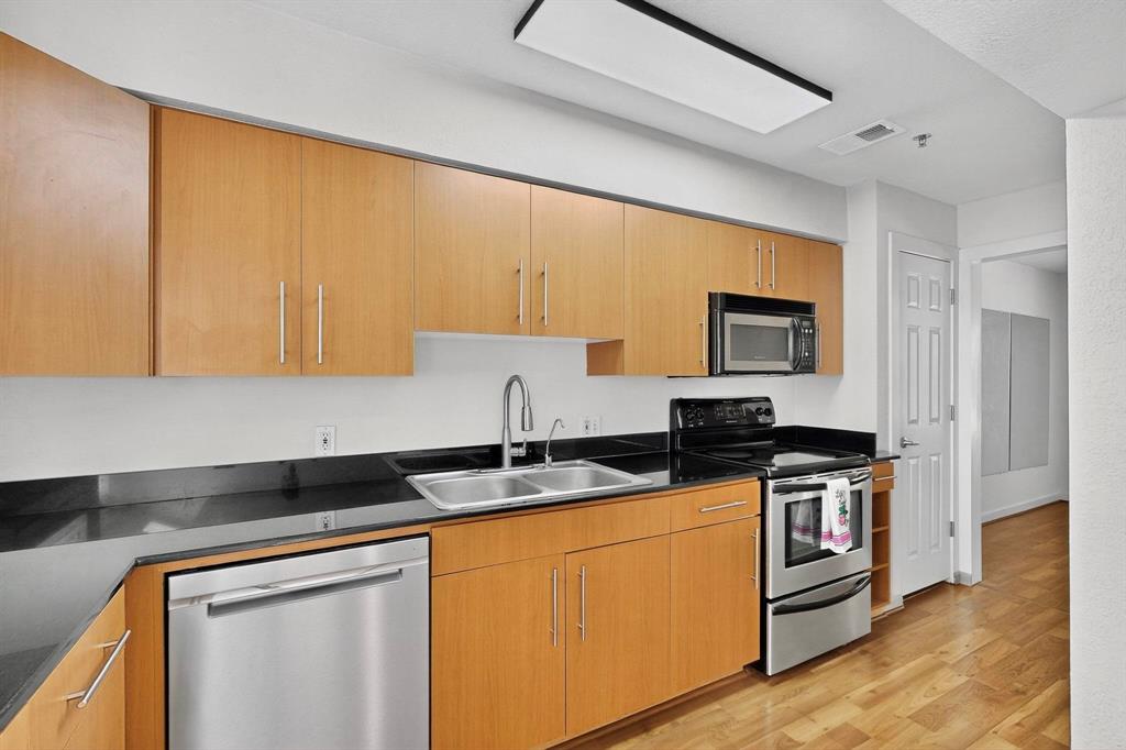 3901 Travis Street, Unit 113 Dallas, TX 75204 - Photo 19 of 40 a kitchen with stainless steel appliances granite countertop a stove a sink and a microwave