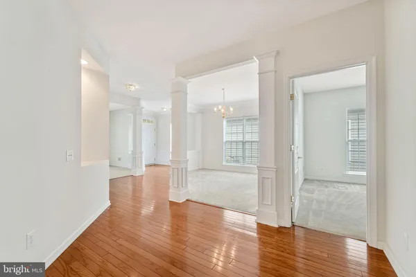 a view of an empty room with wooden floor and a bathroom