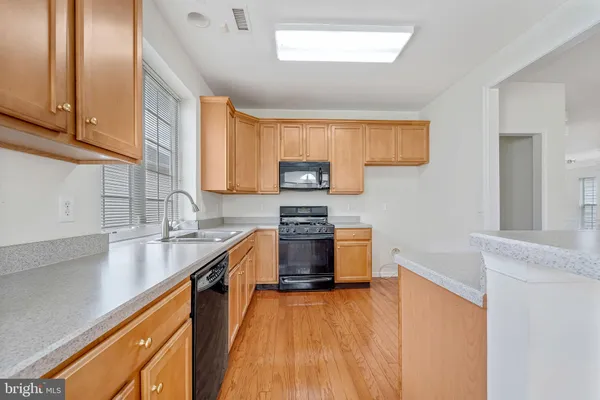 a kitchen with stainless steel appliances granite countertop hardwood floor sink stove and granite counter top