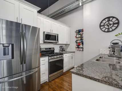 a kitchen with granite countertop stainless steel appliances a sink stove top oven and microwave