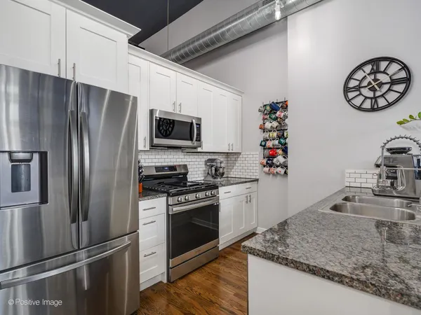 a kitchen with granite countertop stainless steel appliances a sink stove top oven and microwave