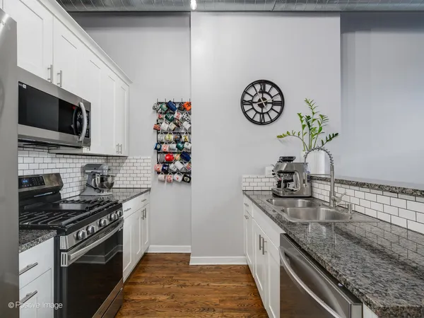 a kitchen with stainless steel appliances granite countertop a sink window and cabinets