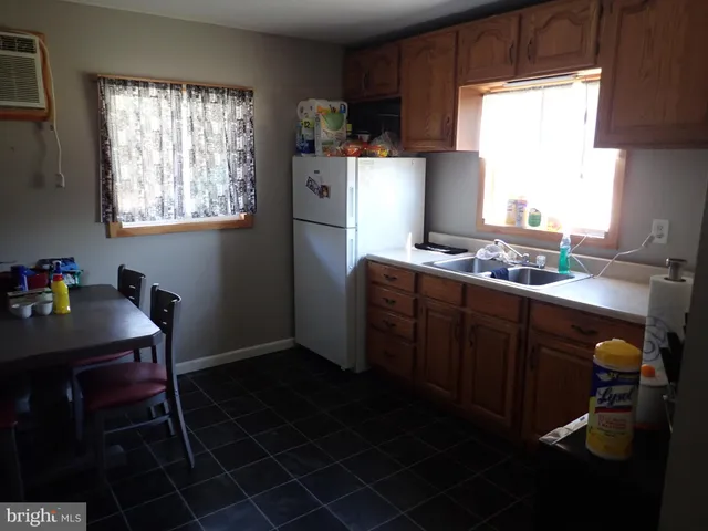 a kitchen with stainless steel appliances granite countertop a sink a stove a refrigerator wooden floor and a dining table