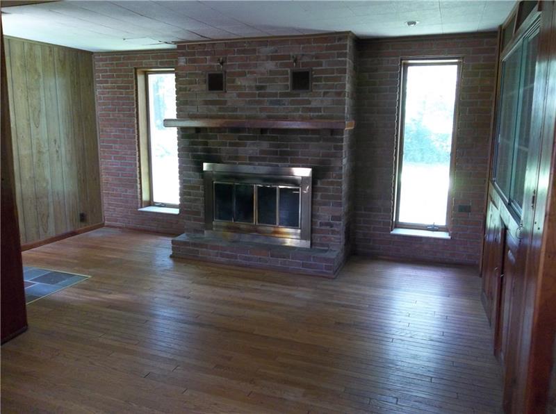 113 Grange Road Rochester, PA 15074 - Photo 3 of 11 The living room features hardwood floors, a wood-burning fireplace, and built-in cabinets.
