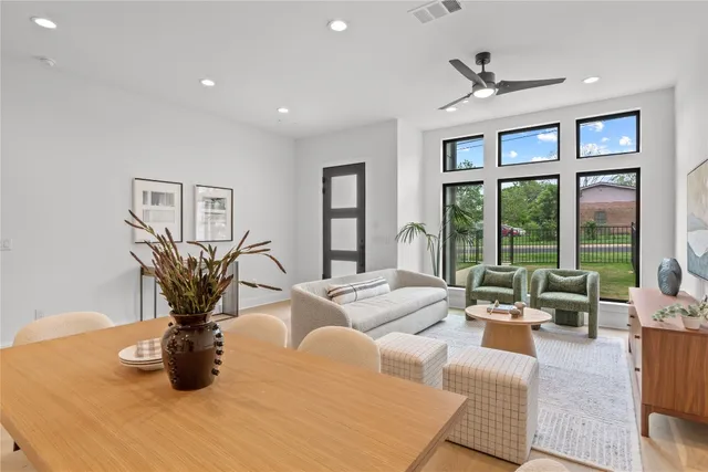 a living room with furniture large window and potted plants