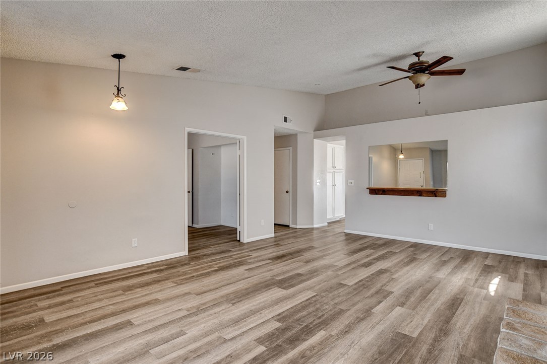 6209 Warm River Road Las Vegas, NV 89108 - Photo 6 of 39 A spacious living area with durable wood-look flooring and a pass-through window to the adjacent kitchen.