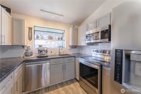 a kitchen with stainless steel appliances granite countertop a sink stove and microwave