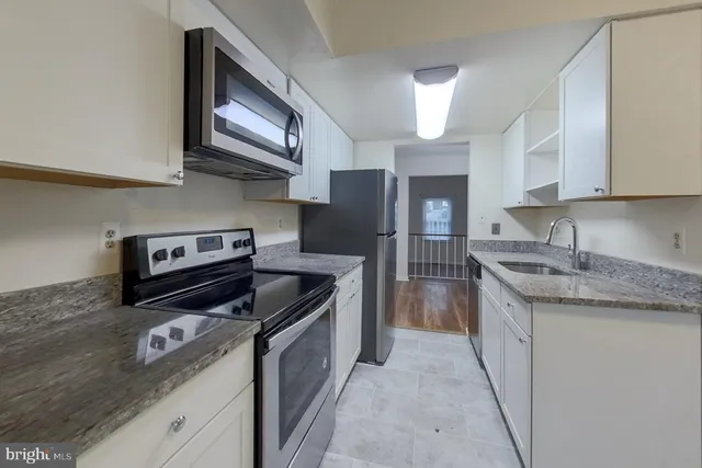 a kitchen with stainless steel appliances granite countertop a stove a sink and a refrigerator