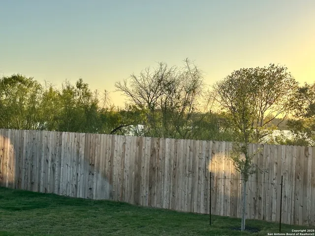 a view of a yard with wooden fence