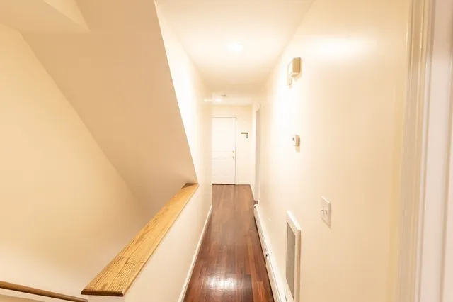 a view of a hallway with wooden floor and a bathroom