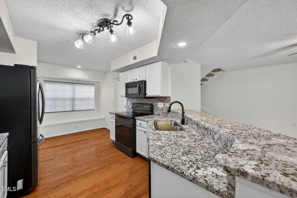 a kitchen with stainless steel appliances granite countertop a sink refrigerator and cabinets