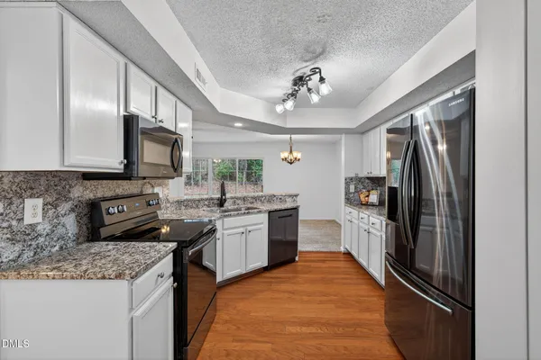 a kitchen with stainless steel appliances granite countertop a sink refrigerator and microwave