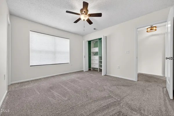 an empty room with ceiling fan and windows