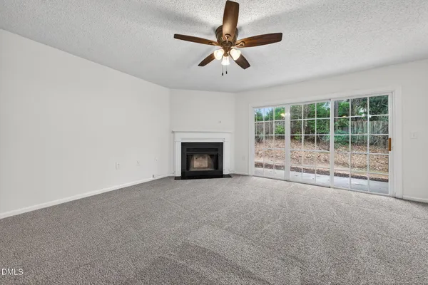 a view of an empty room with a fireplace and a window