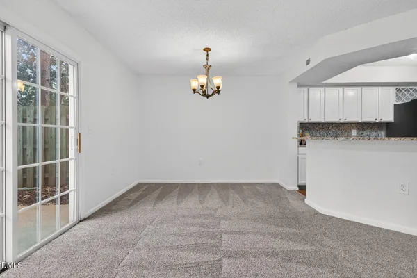 an empty room with kitchen view and windows