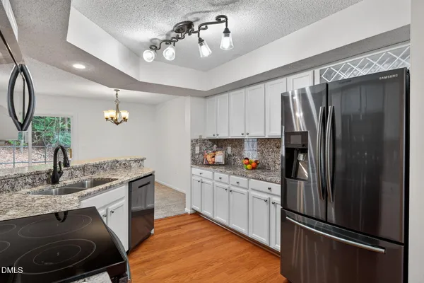 a kitchen with a sink stainless steel appliances and chandelier