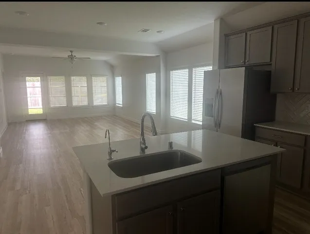 a kitchen with a sink a refrigerator a window and cabinets