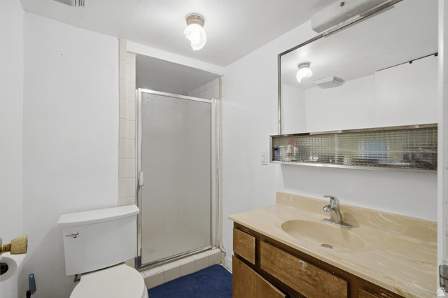 707 East 150 South Provo, UT 84606 - Photo 23 of 31 Bathroom featuring a frosted glass shower enclosure, a vanity with a light-toned countertop and integrated sink, a built-in mirror with integrated shelving, and white walls
