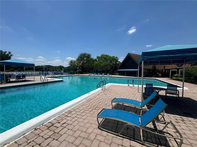 a view of swimming pool with lawn chairs and a yard