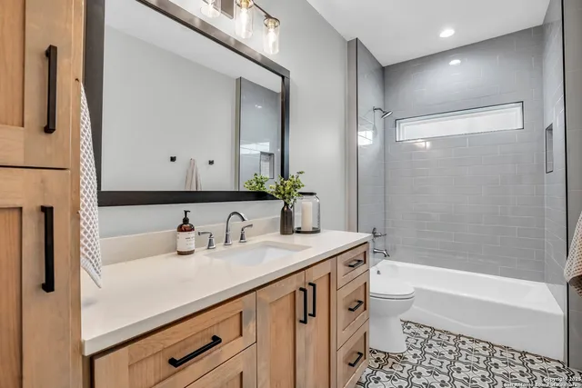 a bathroom with a sink a toilet a mirror a bathtub and shower