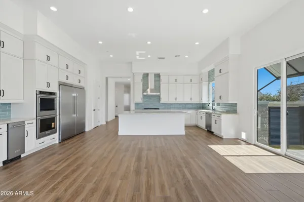 a large kitchen with a center island wooden floor stainless steel appliances and cabinets