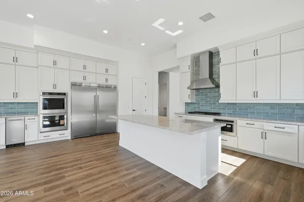 a large kitchen with cabinets wooden floor and stainless steel appliances