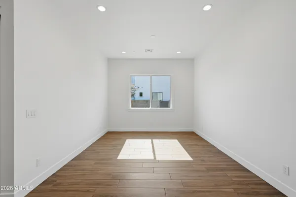 an empty room with wooden floor and windows