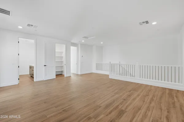 a view of an empty room with wooden floor and closet