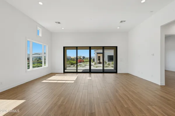 a view of an empty room with wooden floor and a window