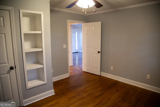 an empty room with wooden floor closet and windows