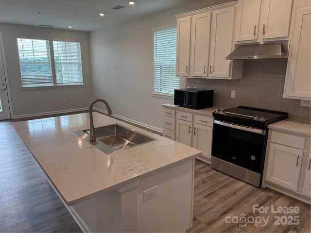 a kitchen with stainless steel appliances granite countertop a sink a stove and a microwave