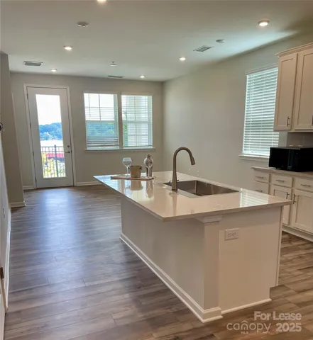 a large kitchen with stainless steel appliances a large counter top a wooden floors and a large window