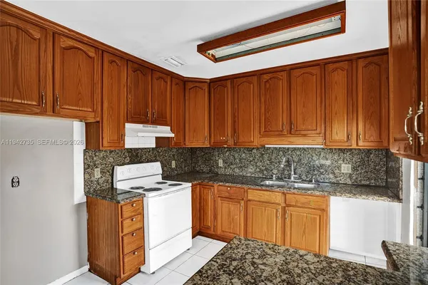 a kitchen with granite countertop wooden cabinets and white appliances