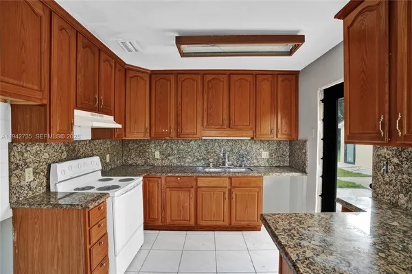 a kitchen with stainless steel appliances granite countertop wooden cabinets a sink and a stove