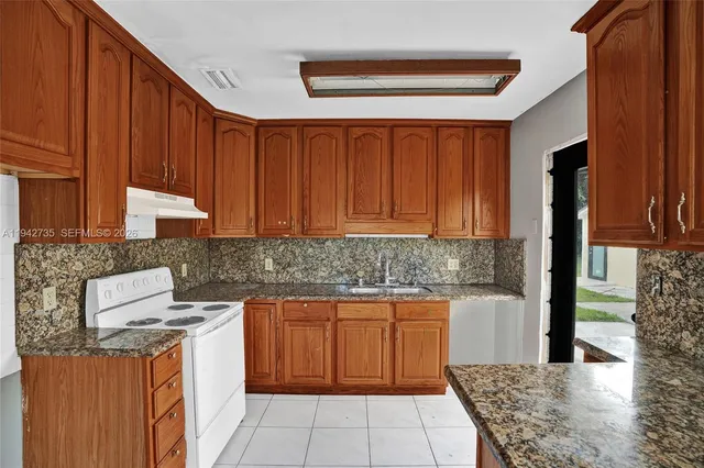 a kitchen with stainless steel appliances granite countertop wooden cabinets a sink and a stove