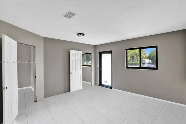 a view of an empty room with closet and a window