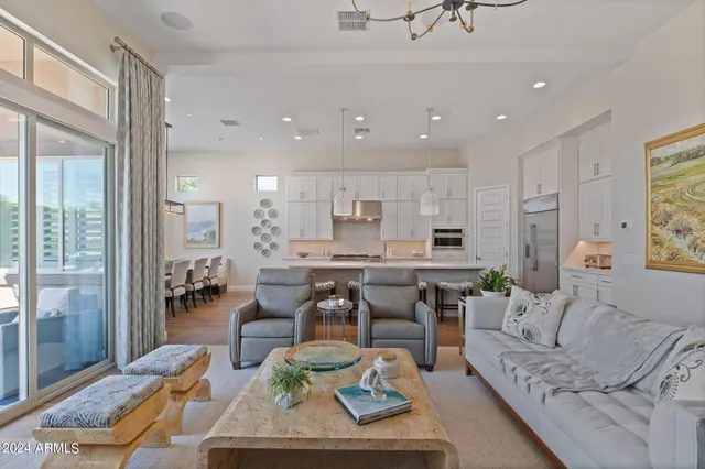 a living room with furniture kitchen view and a large window