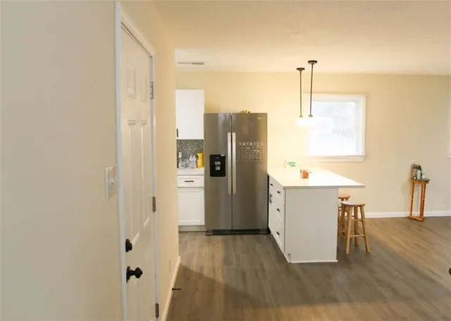 a view of a kitchen with a refrigerator and wooden floor
