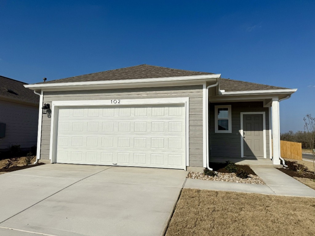 102 Two Bits Lane Elgin, TX 78621 - Photo 1 of 1 Single story home featuring a shingled roof, driveway, and a garage
