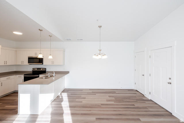 4662 Poplar Way, Unit Q301 Mapleton, UT 84664 - Photo 7 of 18 Kitchen with electric range oven, a peninsula, light wood-type flooring, and stainless steel microwave