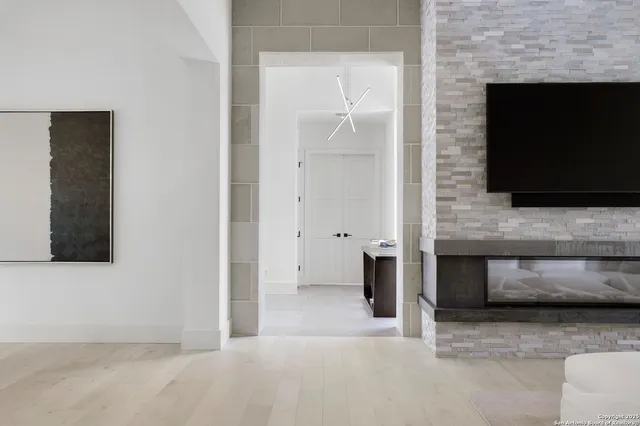 a view of an empty room with wooden floor and a fireplace