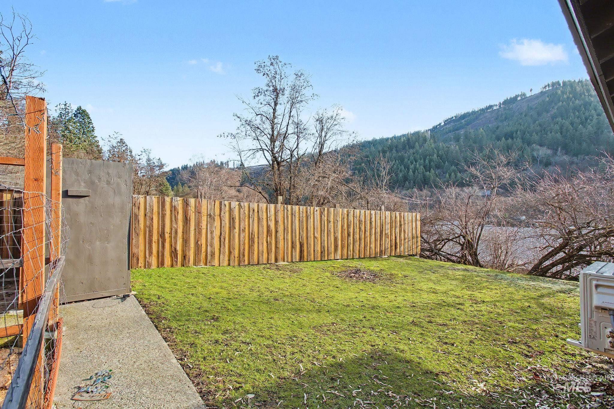 150 Elm Street Orofino, ID 83544 - Photo 1 of 36 Expansive backyard featuring a green lawn, wood privacy fence, and a concrete pathway