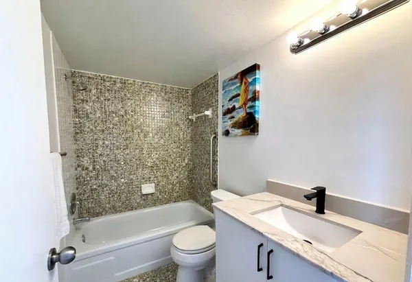 a bathroom with a granite countertop sink a toilet and shower