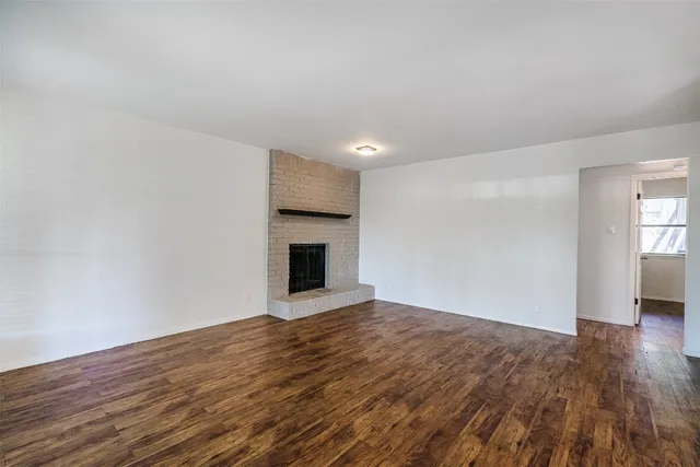 a view of empty room with wooden floor and fireplace
