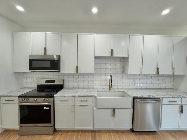 a kitchen with white cabinets and appliances