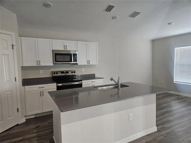 a kitchen with sink a microwave and cabinets